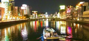 Night view of Nakasu in Fukuoka with neon lights and river cruise boat – a popular nightlife and adult entertainment area in Japan